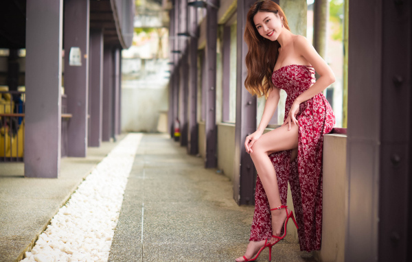 Азиатка в платье стоит у окна