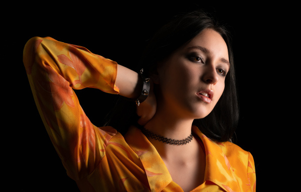 Красивая девушка шатенка с рукой в волосах на черном фоне