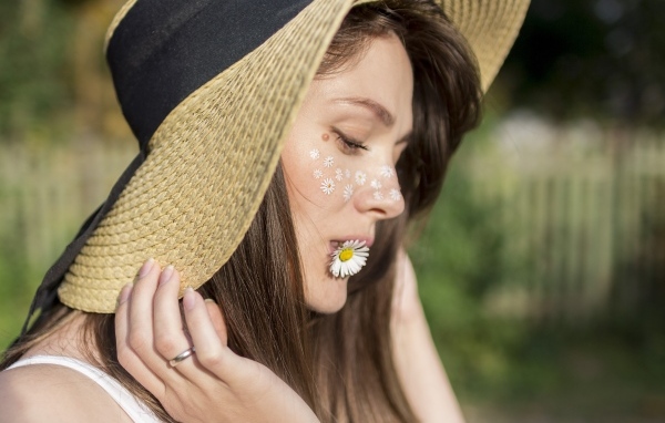 Красивая девушка в соломенной шляпе с ромашкой