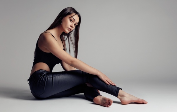 Красивая девушка в черных брюках на сером фоне