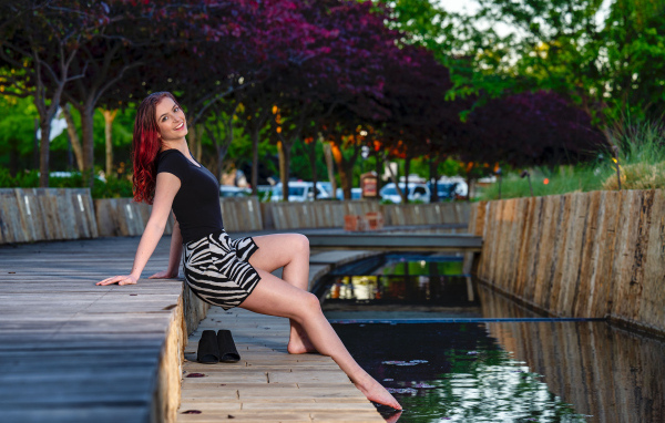 Красивая девушка опустила ноги в воду