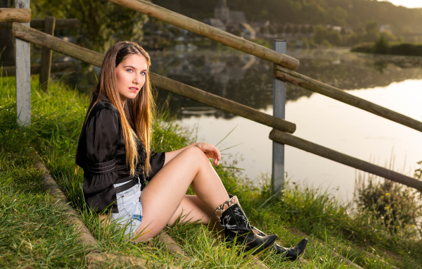 Красивая девушка сидит на берегу реки