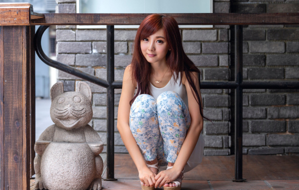 Милая девушка азиатка позирует со статуэткой