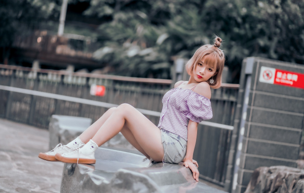 Милая девушка азиатка сидит на камне