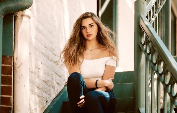 Милая девушка брюнетка сидит на ступеньках