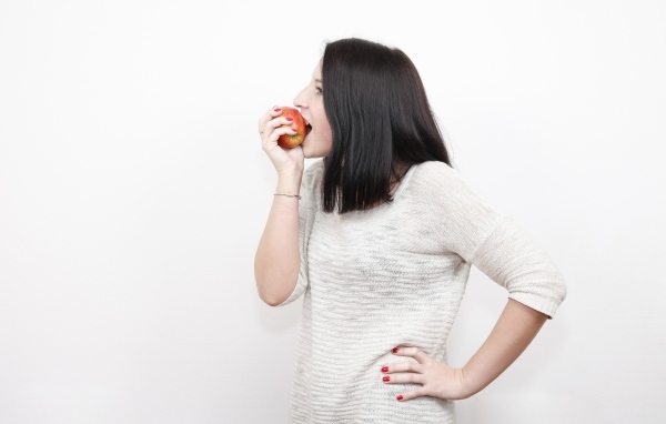 Девушка кусает красное яблоко 