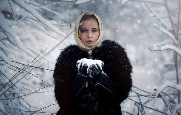 Девушка в черной шубе в заснеженном лесу