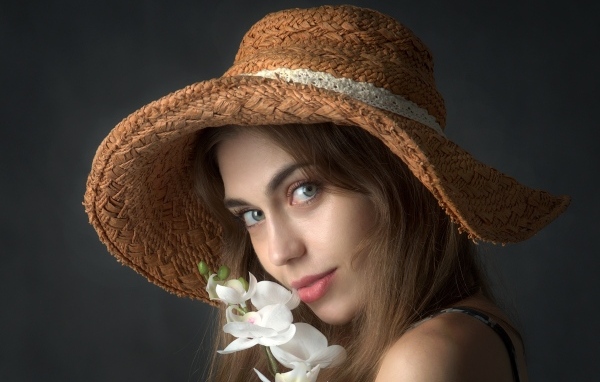 Девушка в шляпе с цветами орхидеи