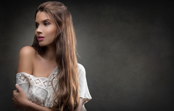 Девушка в белом платье с длинными волосами на сером фоне
