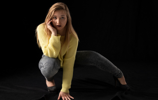 Девушка в желтом свитере на черном фоне