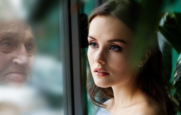 Девушка смотрит на свое отражение в старости