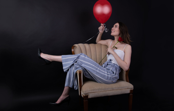 Девушка с шариком и розой сидит в кресле