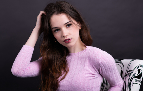 Длинноволосая шатенка в свитере с рукой в волосах