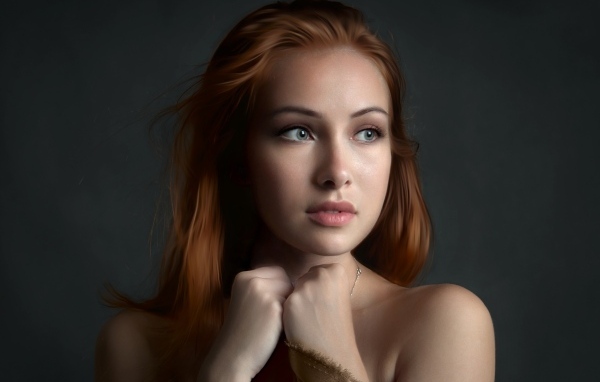 Рыжеволосая девушка с красивыми серыми глазами на сером фоне