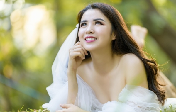 Улыбающаяся девушка азиатка в платье невесты