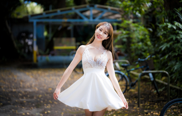 Улыбающаяся азиатка в белом платье в парке