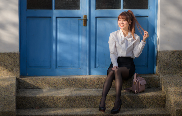 Улыбающаяся азиатка сидит на ступеньках