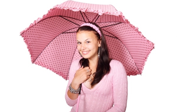 Улыбающаяся девушка с розовым зонтом на белом фоне