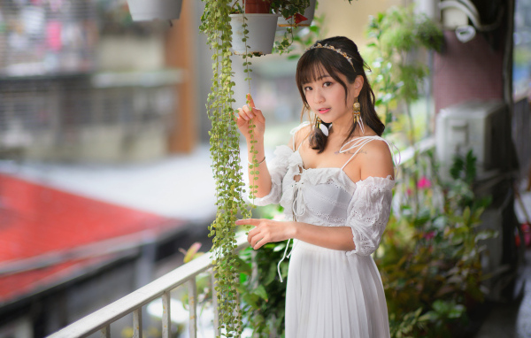 Молодая азиатка в белом платье у растений