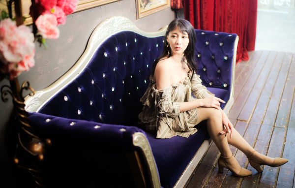 Молодая азиатка сидит на красивом диване