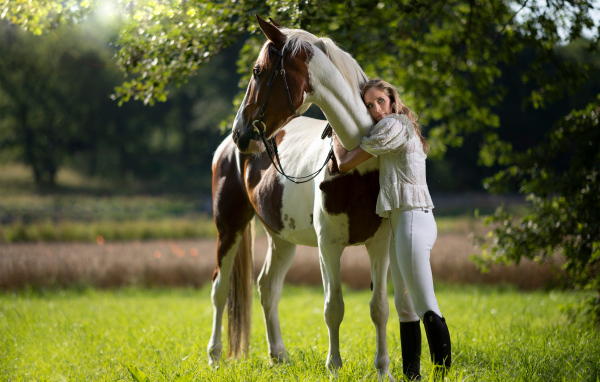 Молодая девушка обнимает большого коня