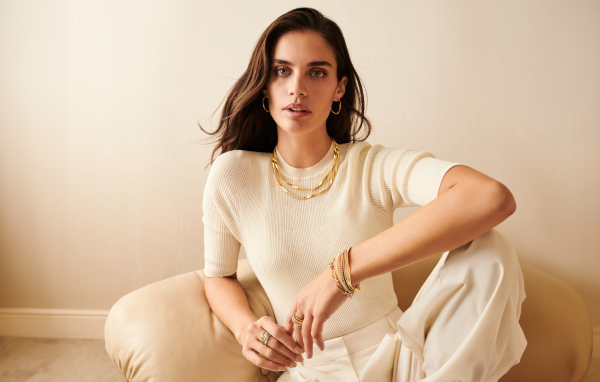 Модель Сара Сампайо в белом наряде сидит в кресле