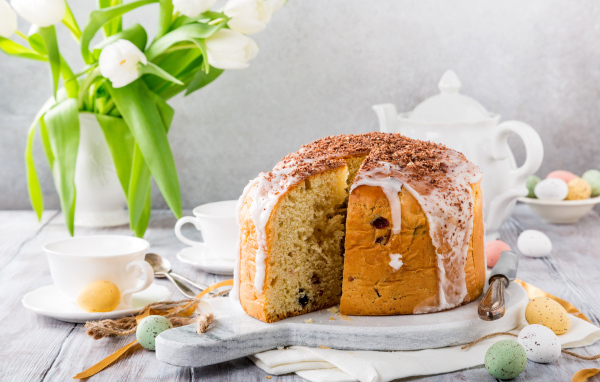 Пасхальный кулич на столе с букетом тюльпанов и сладостями