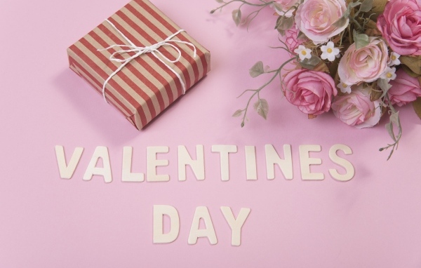 Цветы и подарок на розовом фоне на День Святого Валентина