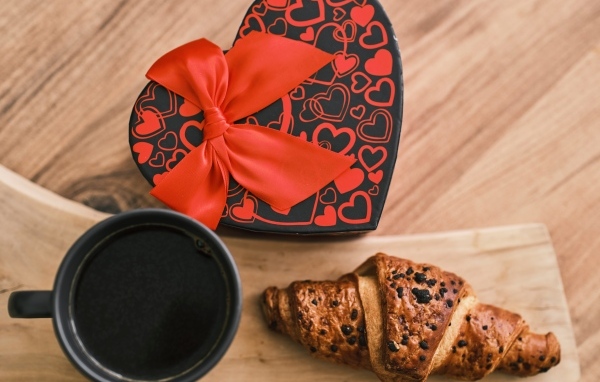 Коробка в форме сердца, кофе и круассан на столе