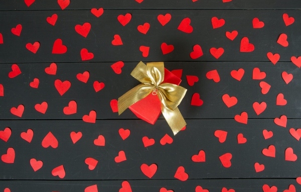 Много маленьких бумажных сердечек с подарком на столе