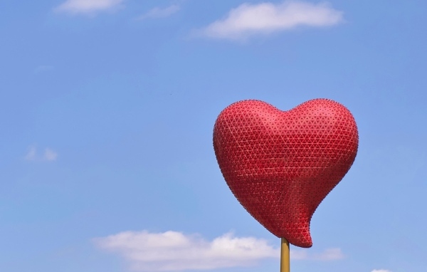 Красное сердце на палочке на фоне неба