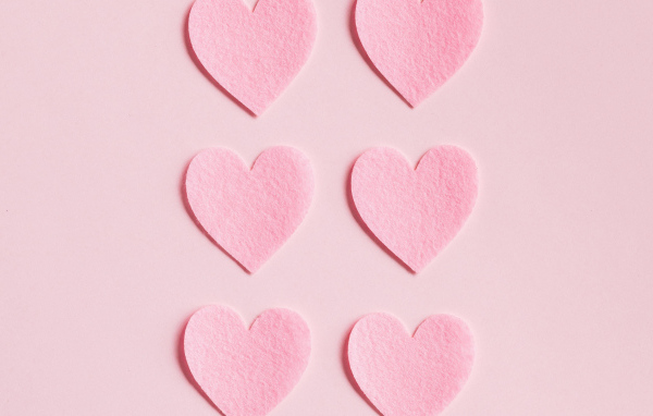 Маленькие бумажные сердечки на розовом фоне