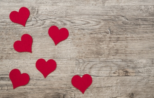 Маленькие красные сердечки на деревянном фоне