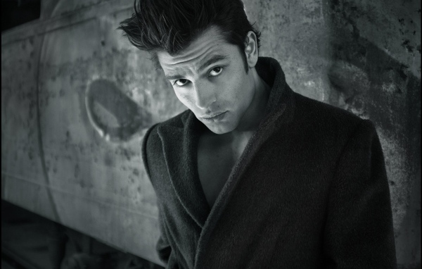 Красивый мужчина в черном пальто у стены