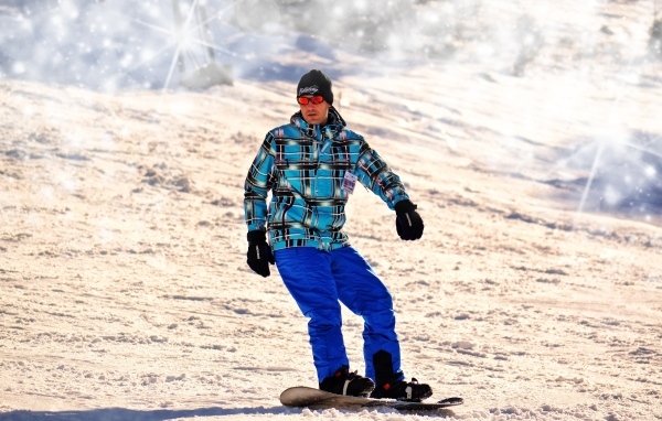 Мужчина сноубордист спускается по склону