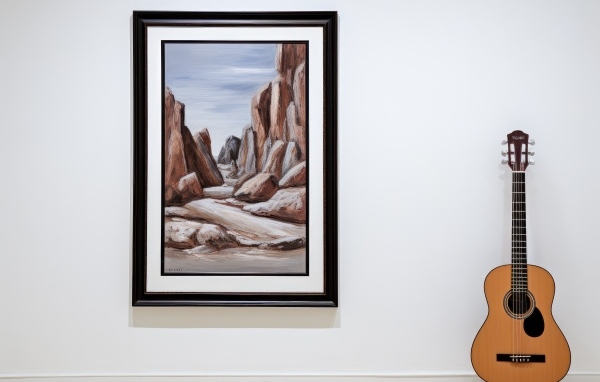 Гитара стоит у стены с большой картиной