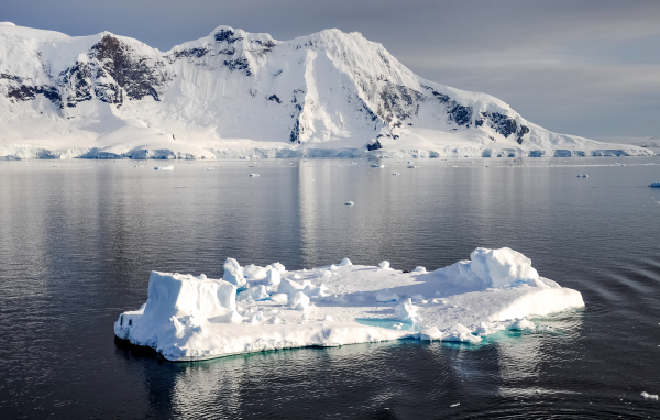 Холодный айсберг в воде у заснеженных гор, Антарктика