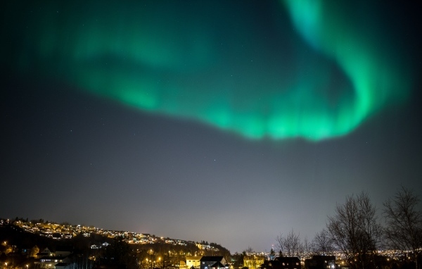 Зеленое полярное сияние в небе над ночным городом