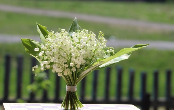 Красивый букет белых ландышей на столе в вазе