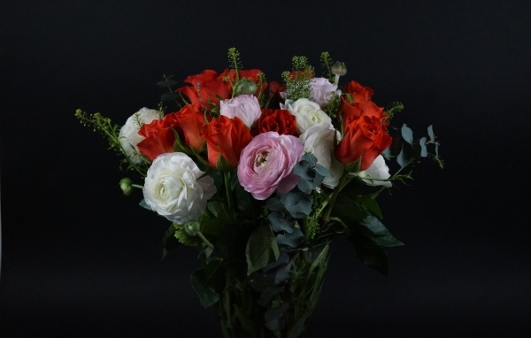 Красивый букет с цветами лютика и красной розы на черном фоне