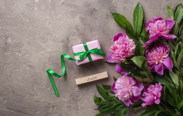 Букет розовых пионов с подарком на сером столе