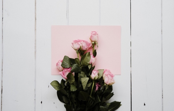 Букет роз с розовым листом бумаги на столе