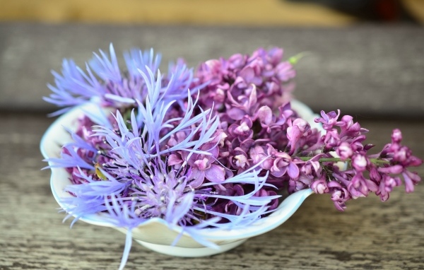 Цветы сирени и василька в вазе на столе