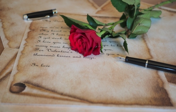 Красная роза с запиской и ручкой на столе