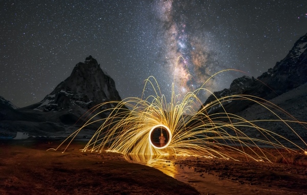 Огненное шоу под ночным красивым небом в горах