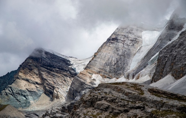 Высокие каменные горы в белых облаках