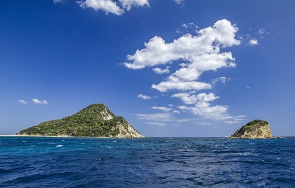 Покрытые зеленью горы в море под голубым небом