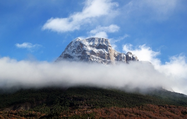 Заснеженная горная вершина в белых облаках