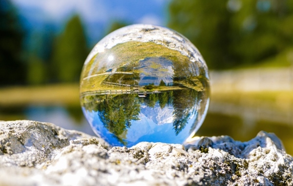 Стеклянный шар стоит на камне у воды