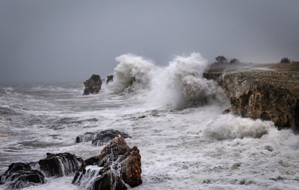 Белые пенные волны бьются об камни во время шторма